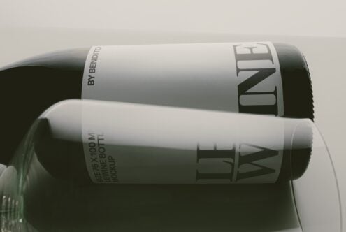 Two wine bottles stacked showing label mockups with minimalist branding on soft neutral background