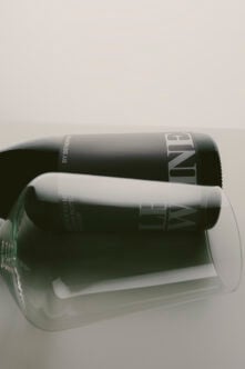 Two black cylinder cosmetic bottles stacked on minimal white background