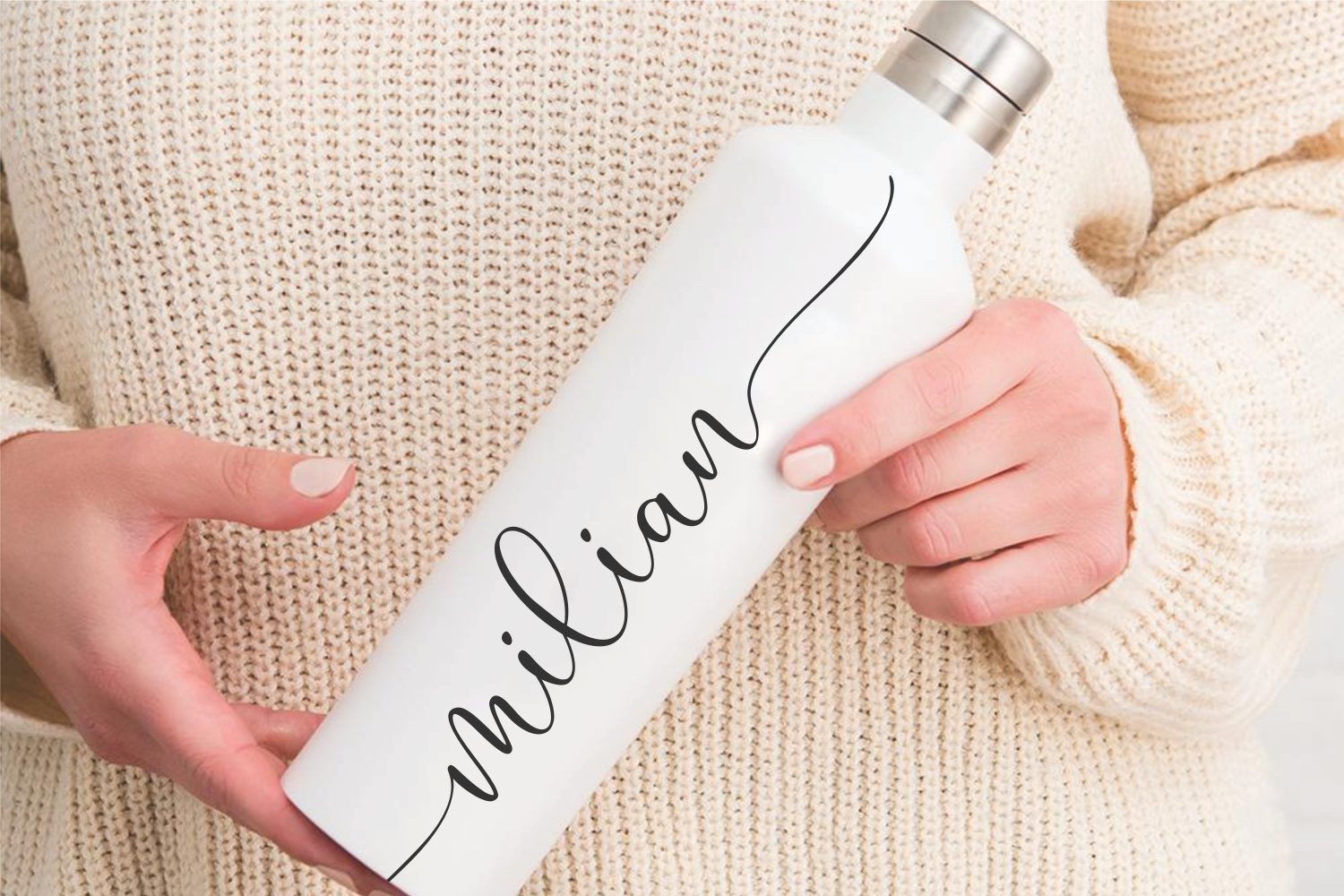 White water bottle with "mindful" script text held in hands over cream knit sweater background