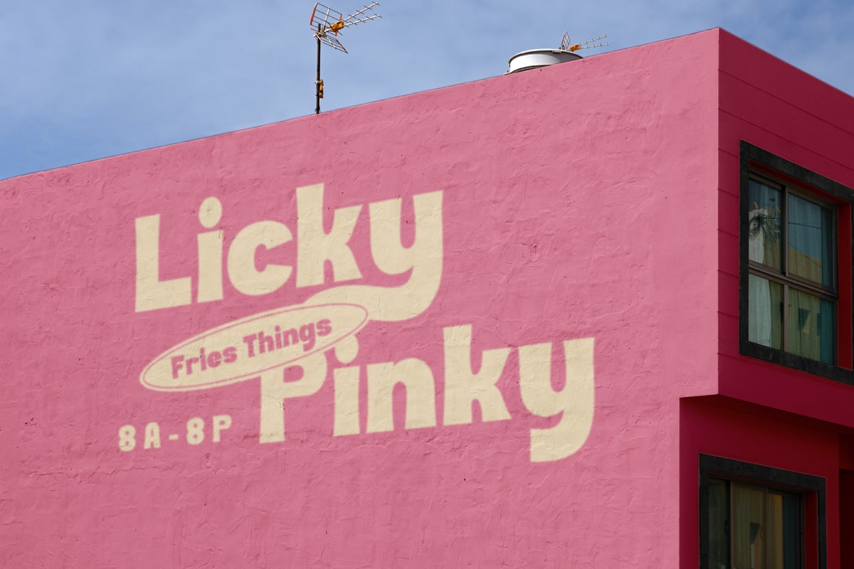 Retro pink building facade with vintage neon sign saying "Licky Pinky Fries Things" in cream lettering
