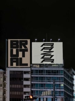 Nighttime shot of two bold rooftop signs lit up over city buildings with geometric typography
