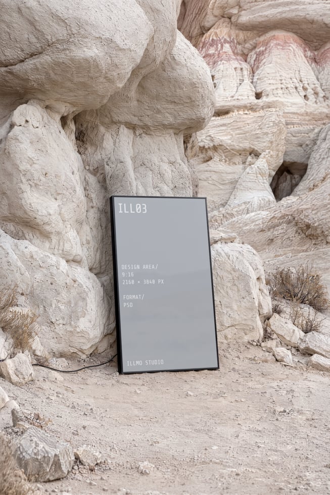 Vertical phone mockup leaning against massive white rock formations in desert landscape with sandy ground