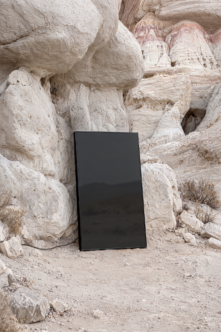 Blank tablet leaning against weathered white rock formations in desert landscape mockup