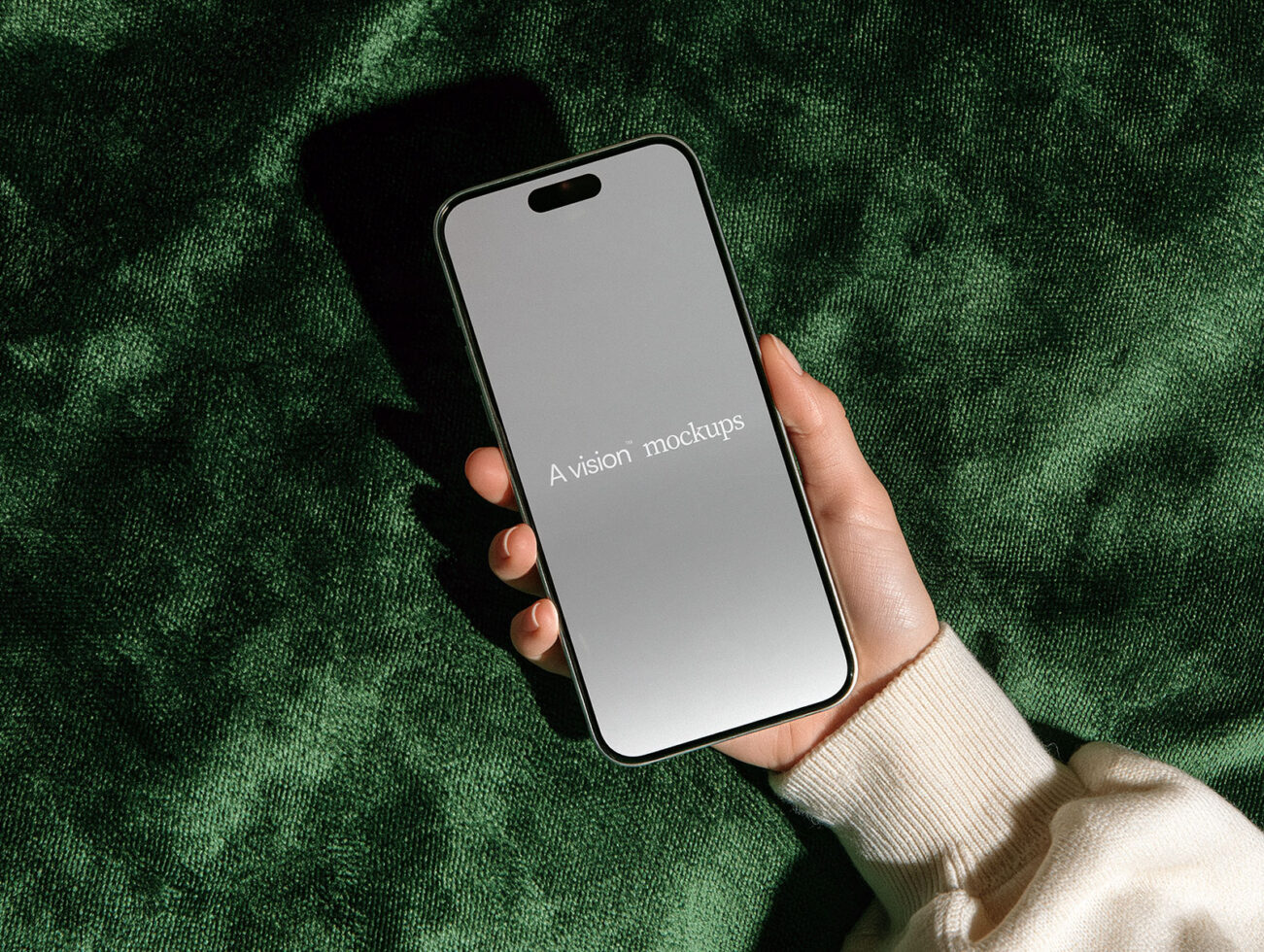 Hand holding iPhone 14 Pro with blank screen on green textured fabric background