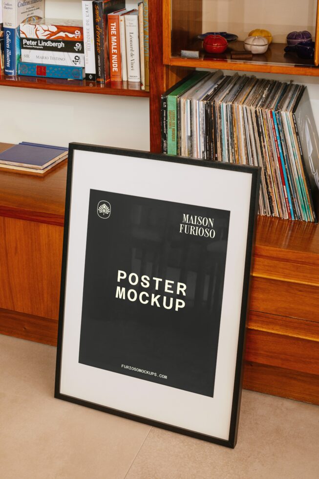 Framed poster leaning against wood shelving with books, CDs, plus colorful decorative bowls on display