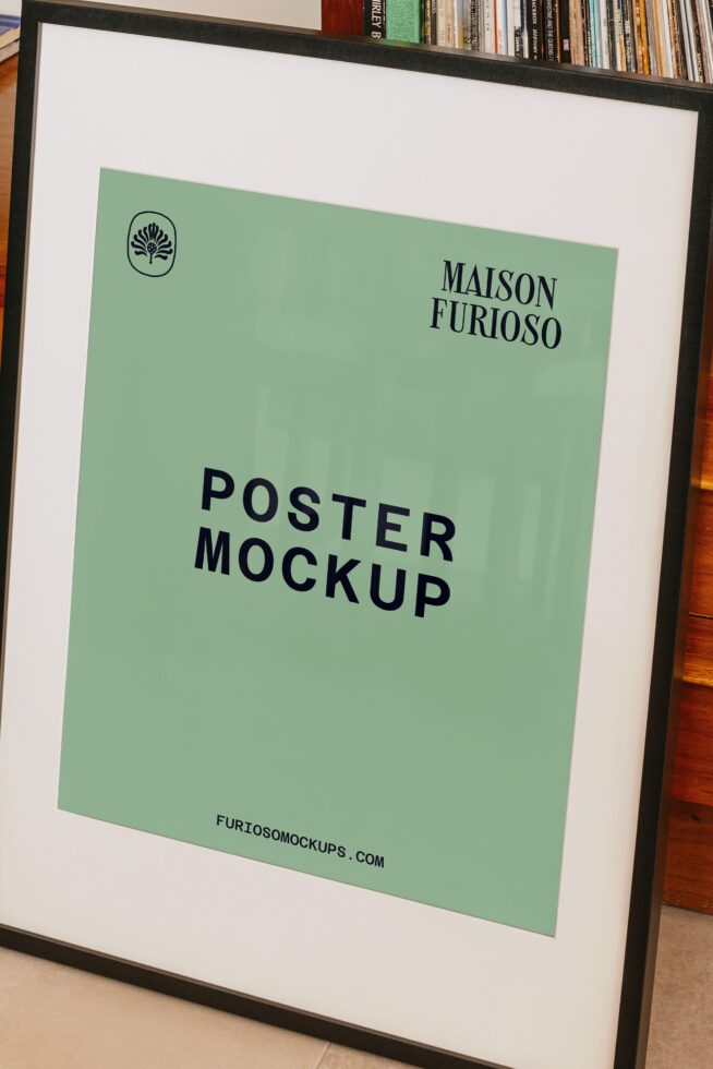 Framed poster mockup with sage green paper, black border, books on shelf in background