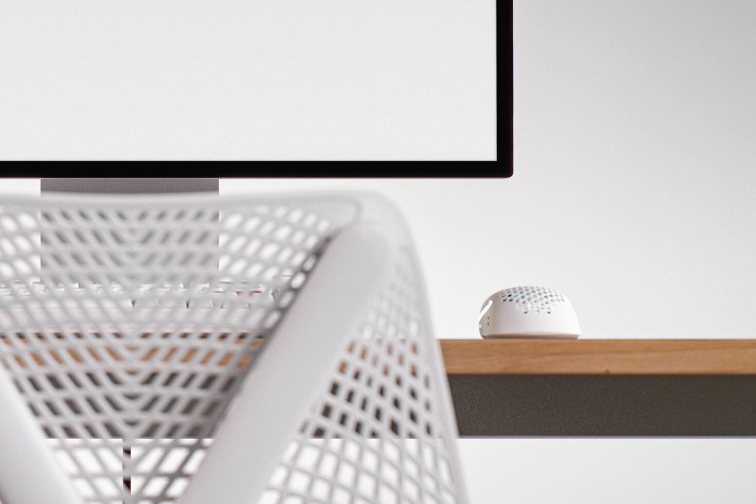 Clean desk setup with monitor, wireless mouse, modern speaker on wood shelf