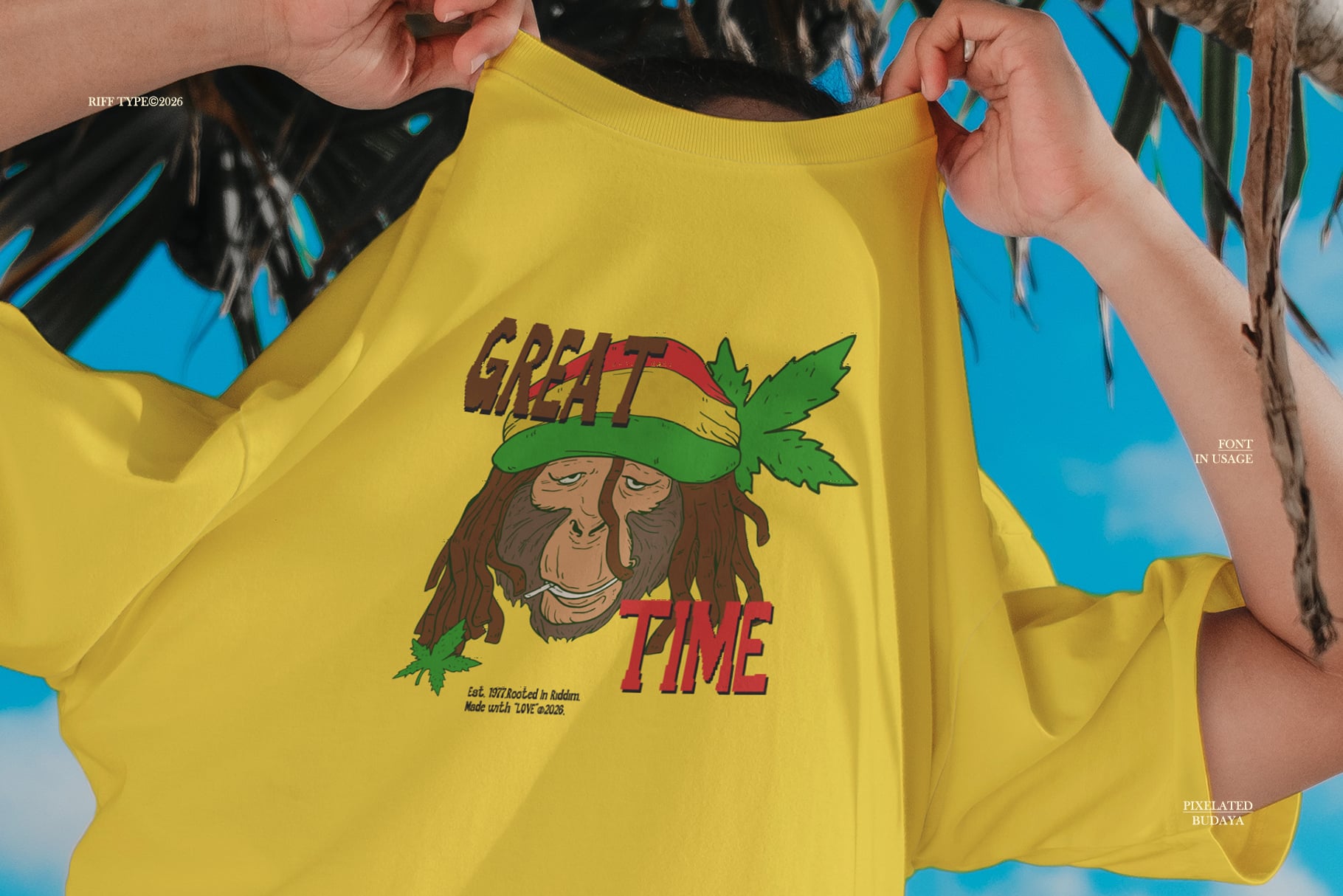 Bright yellow tee with groovy rastafarian character graphic, hands holding shirt open against blue sky backdrop