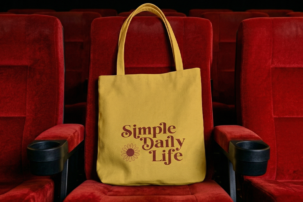 Mustard tote bag with "Simple Daily Life" text sitting on red movie theater seat