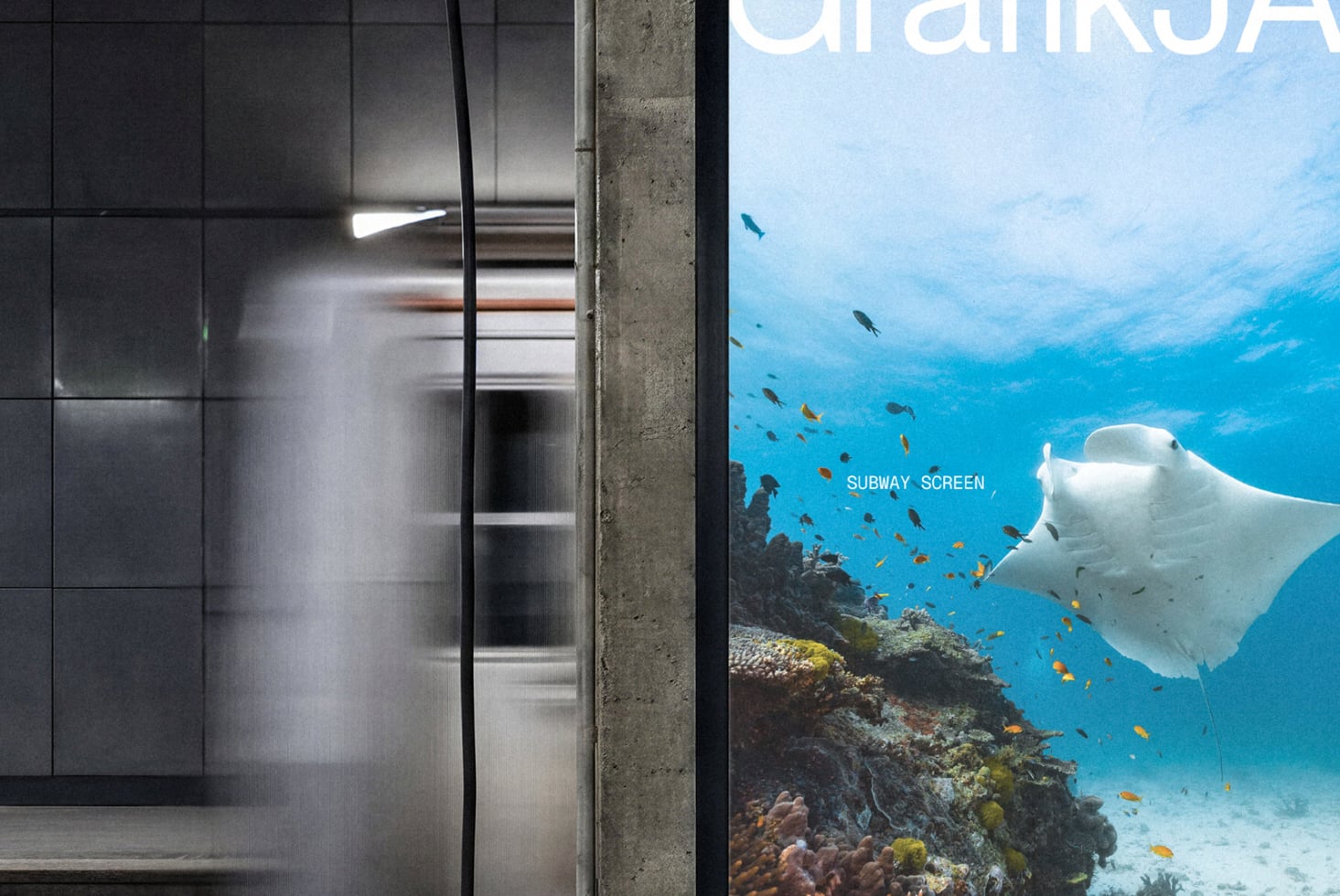 Subway station digital screen showing underwater manta ray with tropical fish swimming above coral reef