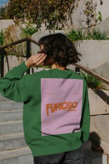 Person wearing bright green sweatshirt with pink back print showing Furioso Mockups branding in orange type