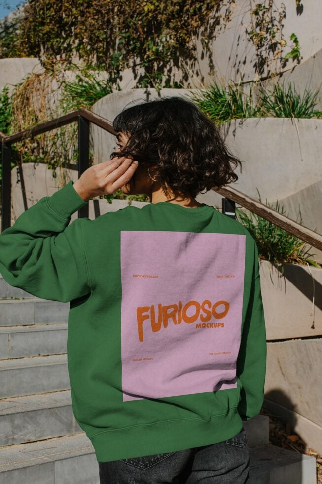 Person wearing bright green sweatshirt with pink back print showing Furioso Mockups branding in orange type
