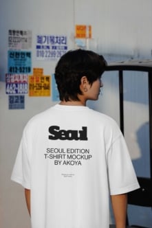 Person wearing white tee with Seoul back print standing in front of Korean street signs