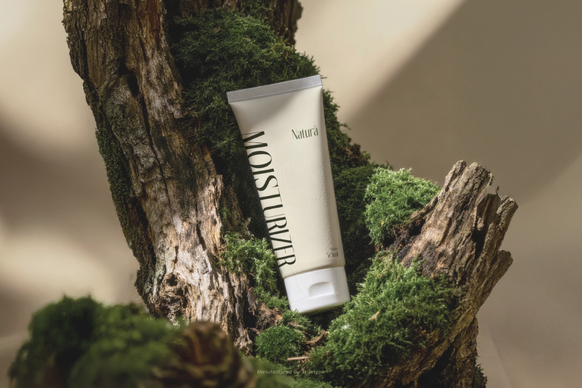 White skincare tube nestled in moss-covered bark with natural sunlight casting shadows