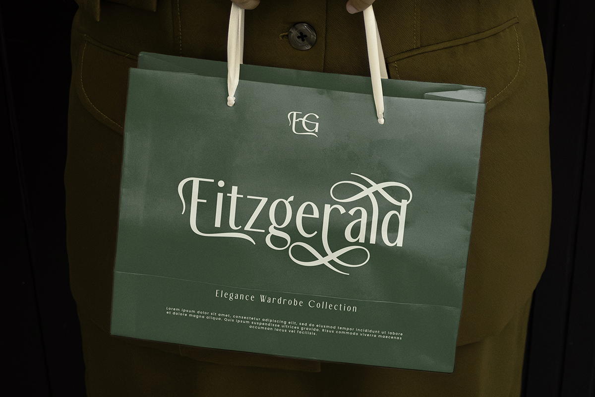 Sage green shopping bag mockup with ornate Fitzgerald logo on olive jacket background